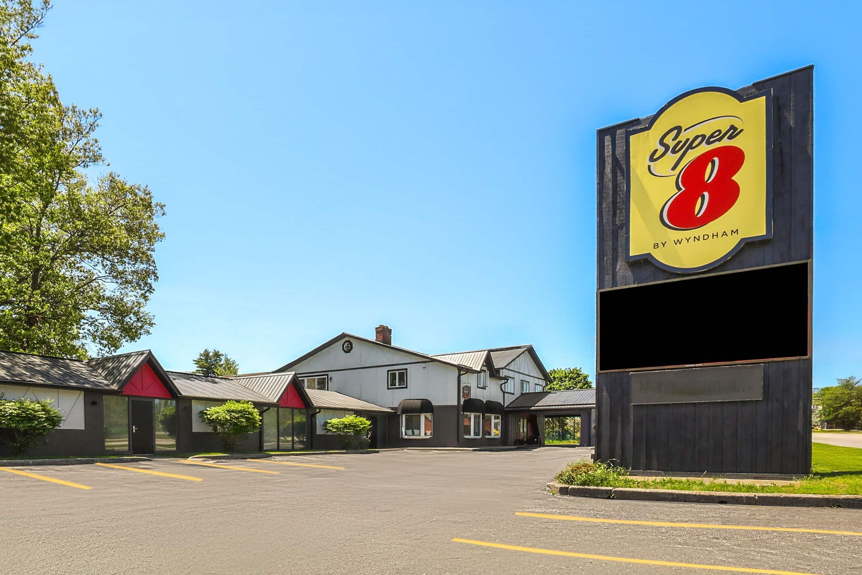 Un motel Super 8 con un grande cartello, un parcheggio e un edificio con diverse camere.