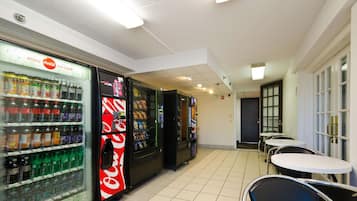 A vending area with various drink options, including Coca-Cola and other beverages. There are tables and chairs for seating.