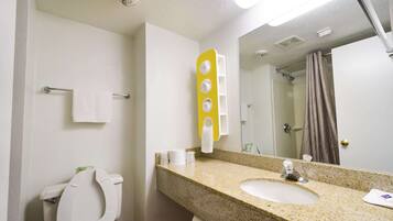 A bathroom with a white toilet, a sink, a mirror, and a shower.