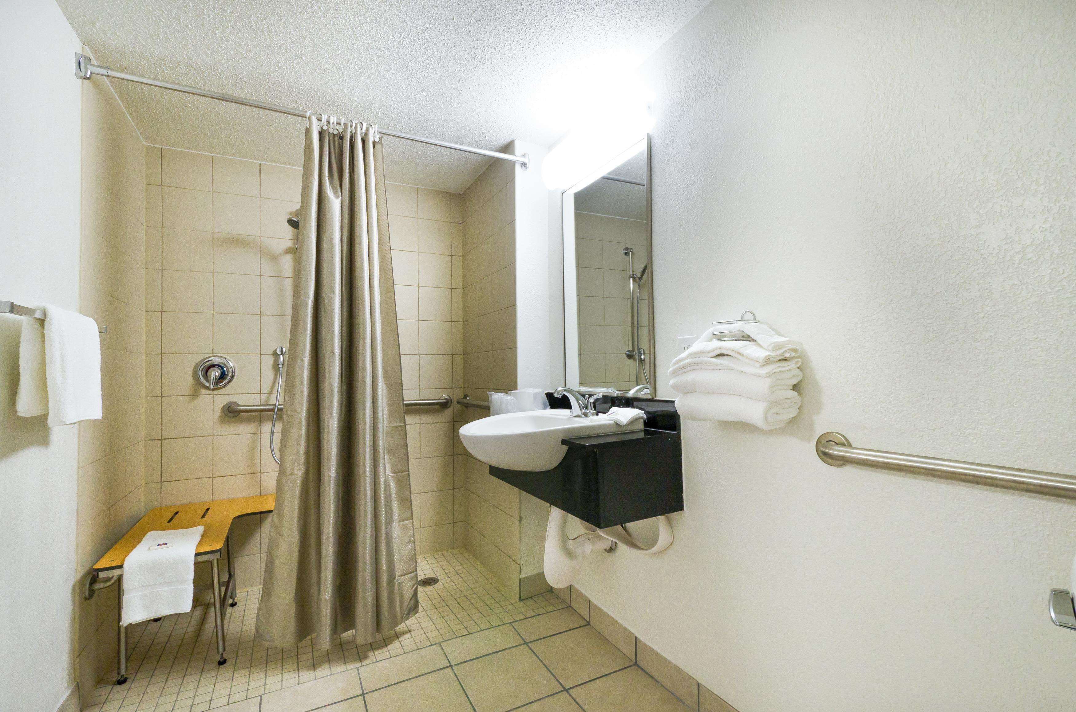 Ein Badezimmer mit Dusche, Waschbecken, Spiegel und Handtuchhalter.