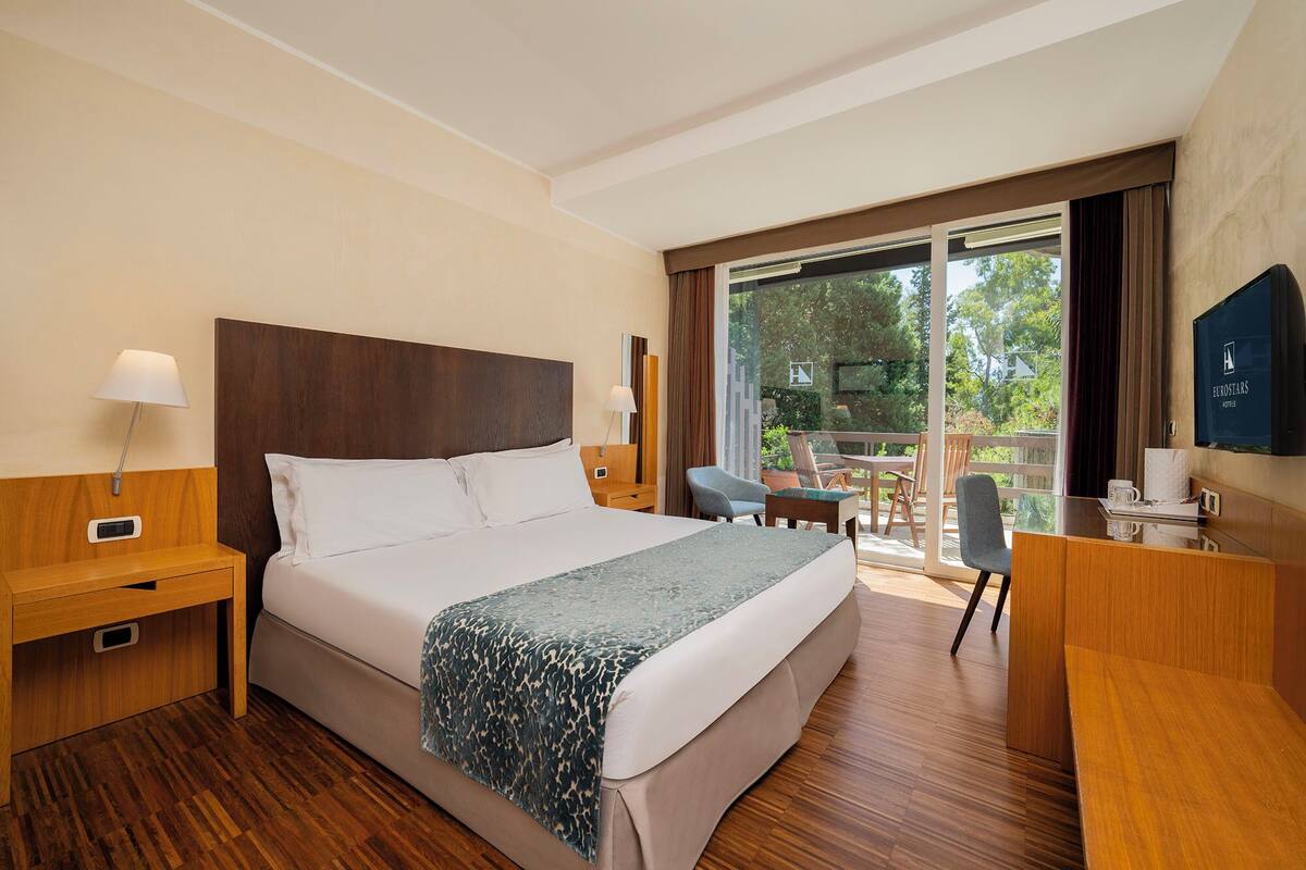 Una habitación de hotel con una cama grande, un escritorio, una silla y un televisor.