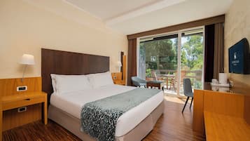 A hotel room with a large bed, a desk, a chair, and a TV.