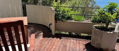 A wooden deck with a chair, a planter, and a railing overlooking a scenic view.