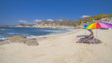 Une plage avec un parasol coloré et une chaise de plage.
