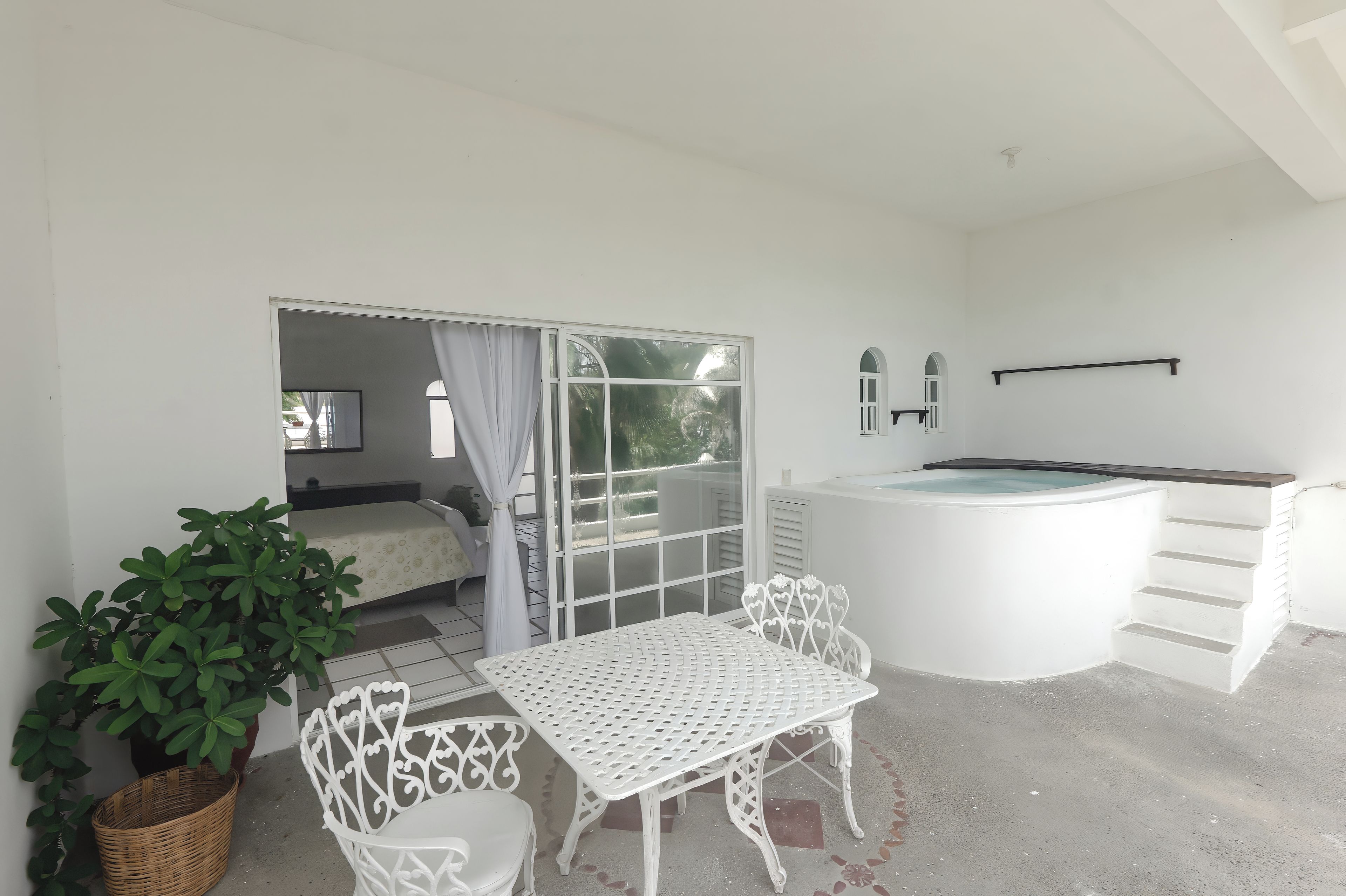 Une chambre avec un lit, une table et des chaises, un jacuzzi et une plante en pot.