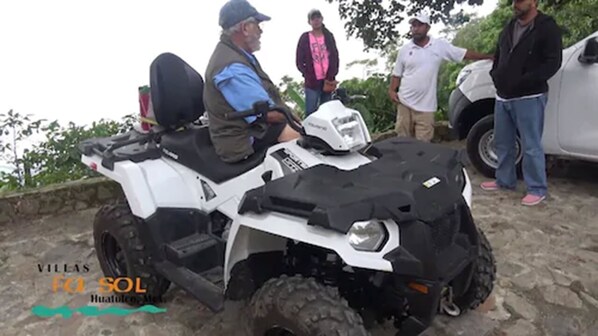 A white ATV with a black front and side panels, parked on a stone surface. - Villas Fa-Sol (Santa María Huatulco)