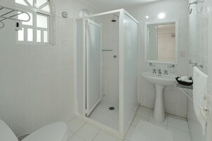Un baño con ducha, inodoro, lavamanos y espejo.