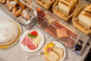 Bőséges reggeli büfé, melyben különféle ételek – például sütemények, kenyér, valamint számos sajt- és hútfajta – található.