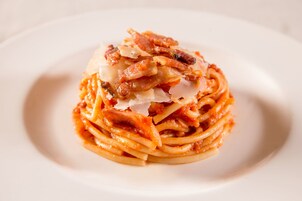 A plate of spaghetti with tomato sauce and grated cheese.