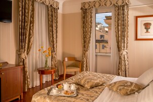 Una camera d'hotel con un letto, una sedia di legno, un tavolino con un vassoio per la colazione e una finestra con tende.