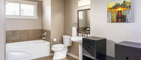 Un baño moderno con bañera, inodoro, lavabo y espejo.