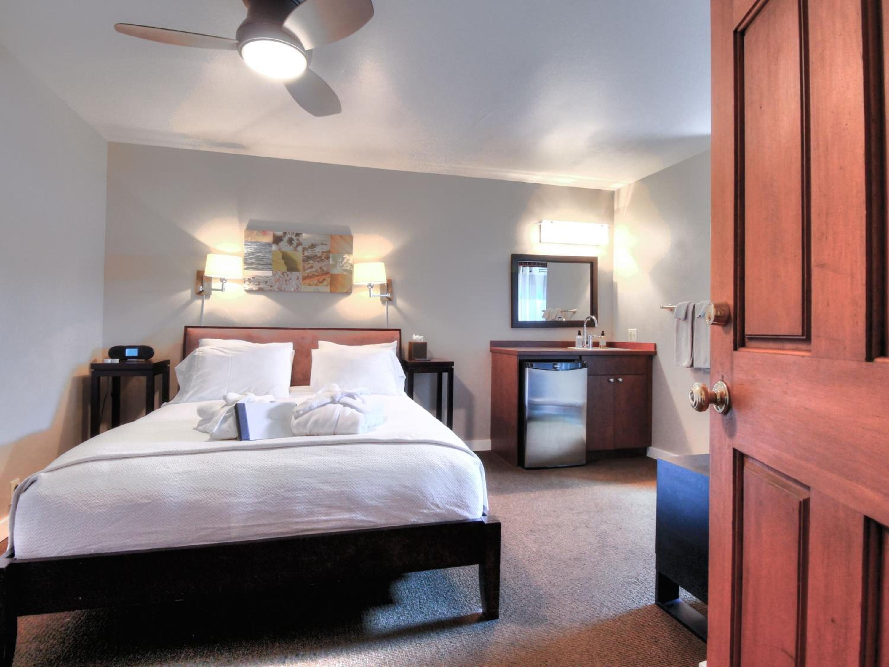 Een hotelkamer met een bed, een bureau, een spiegel en een kledingkast.