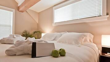 A bedroom with a bed, a laptop, and two apples on the bed.
