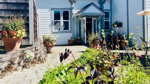 A white building with a balcony, potted plants, and a stone pathway. - Bird Rock Hotel (Friday Harbor)