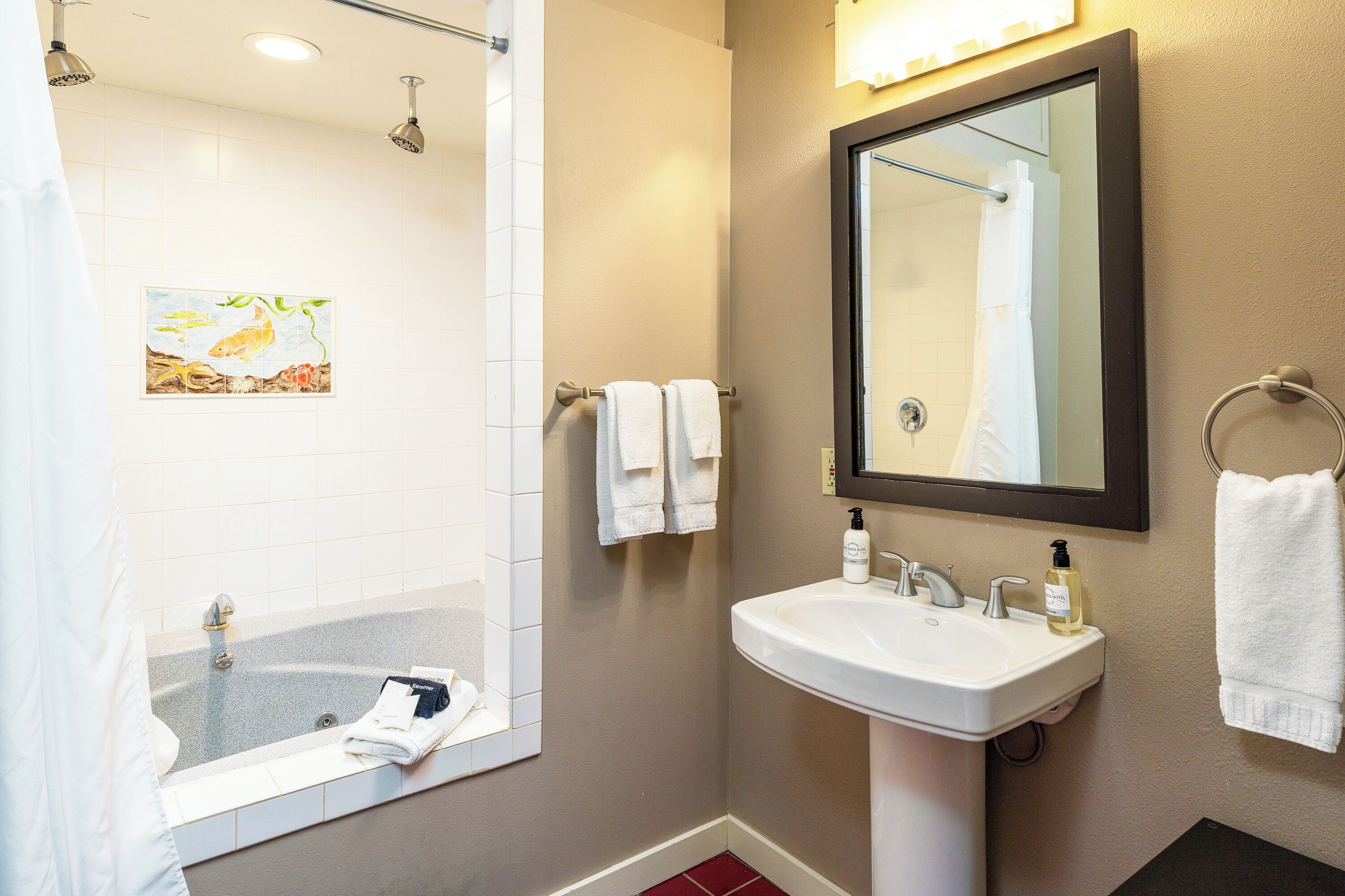 A bathroom with a bathtub, a sink, a mirror, and a towel rack.