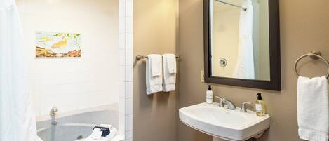 A bathroom with a bathtub, a sink, a mirror, and a towel rack.