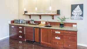A kitchen with wooden cabinets, a built-in microwave, and a coffee station. - Bird Rock Hotel (Friday Harbor)