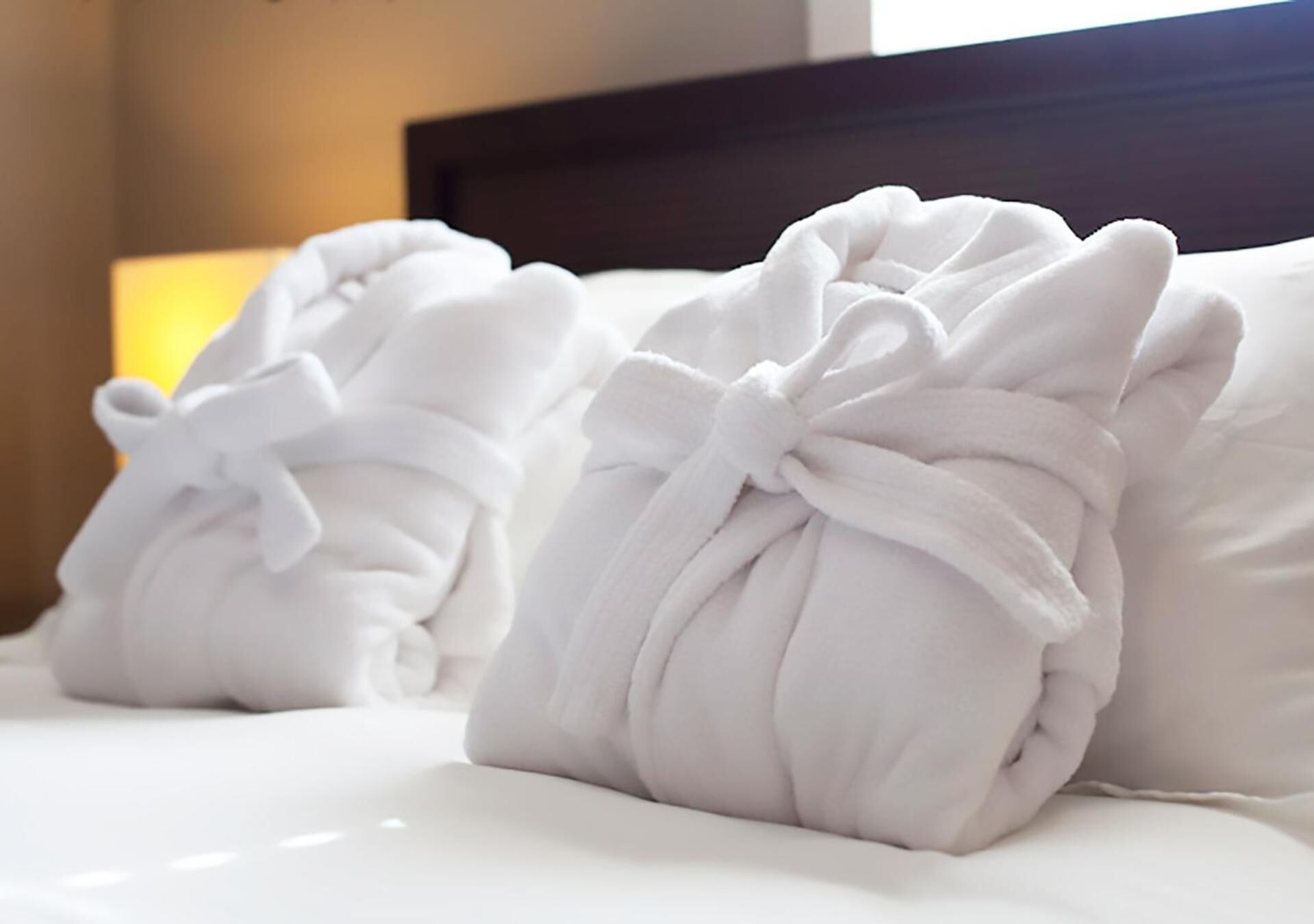 Neatly folded white towels with bows on a bed.