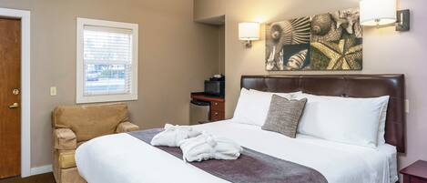 Ein Hotelzimmer mit einem großen Bett, einem Sessel, einem Schreibtisch und einem Wandbild.