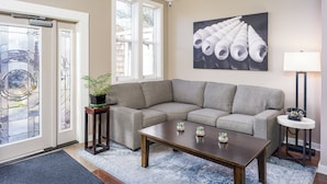 A living room with a sectional sofa, a coffee table, a lamp, and a potted plant. - Bird Rock Hotel (Friday Harbor)
