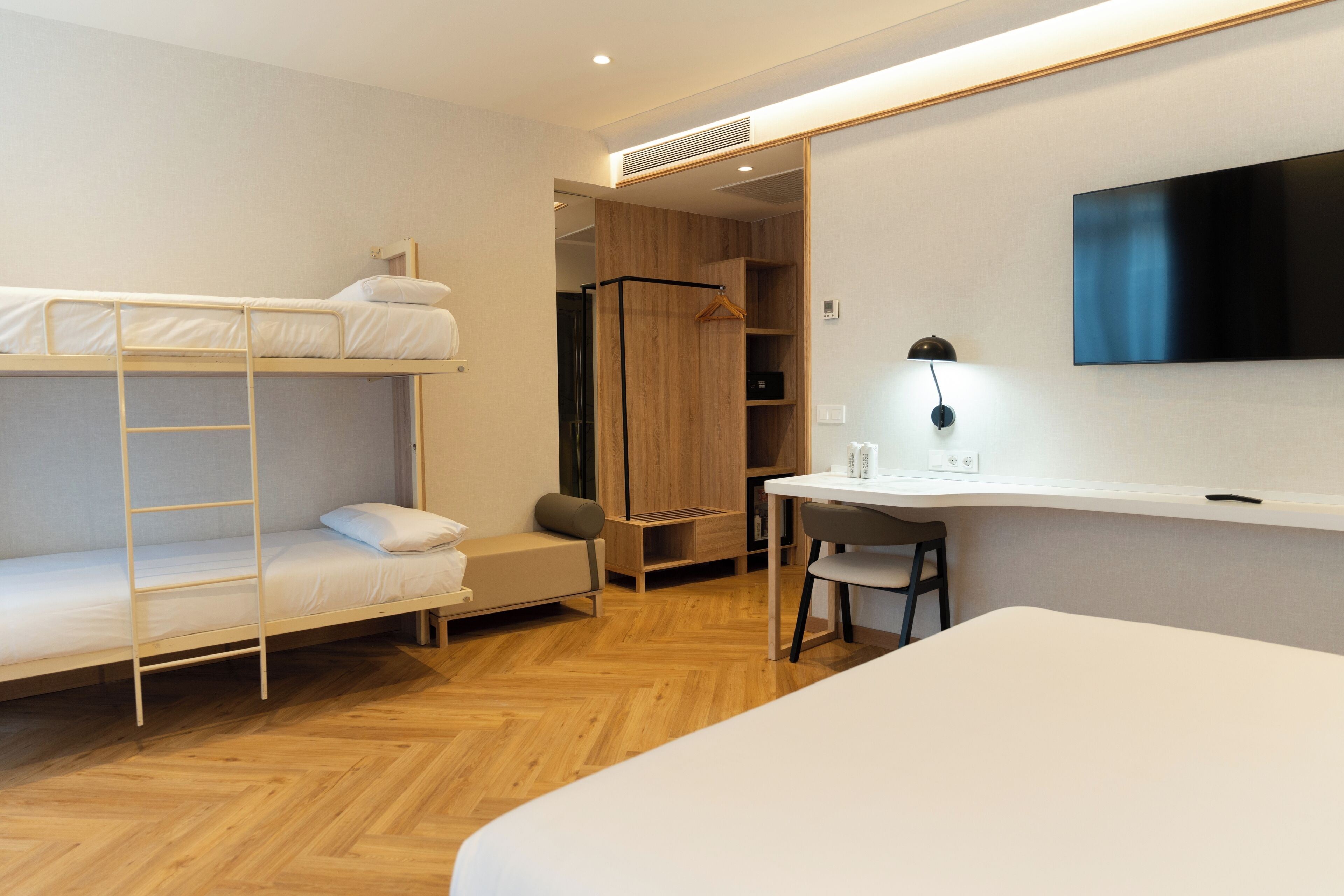 Un dormitorio con literas, un escritorio, una silla, un televisor y un armario.