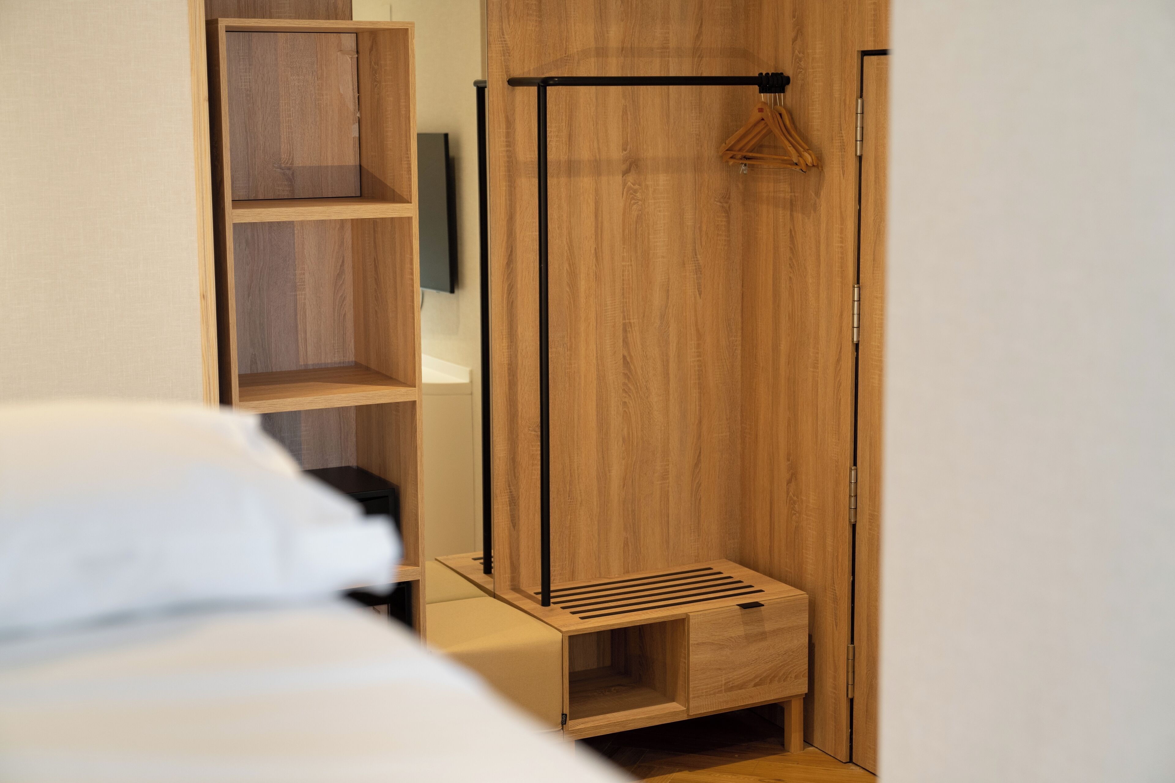 Un dormitorio con un armario de madera, un perchero y una cama.