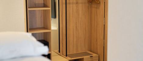 Un dormitorio con un armario de madera, un perchero y una cama.