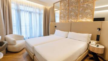 Habitación de hotel con una cama grande, una silla, una mesita de noche con teléfono y un panel decorativo sobre la cama.