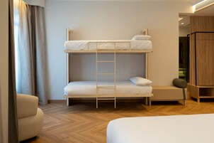 A bunk bed with a ladder, a bedside table, and a chair in a room with wooden flooring and a wooden wardrobe.