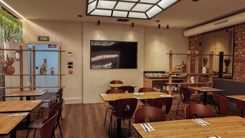 Ein Restaurant mit Holztischen und -stühlen, einem großen Fernsehbildschirm und einer Ziegelwand.