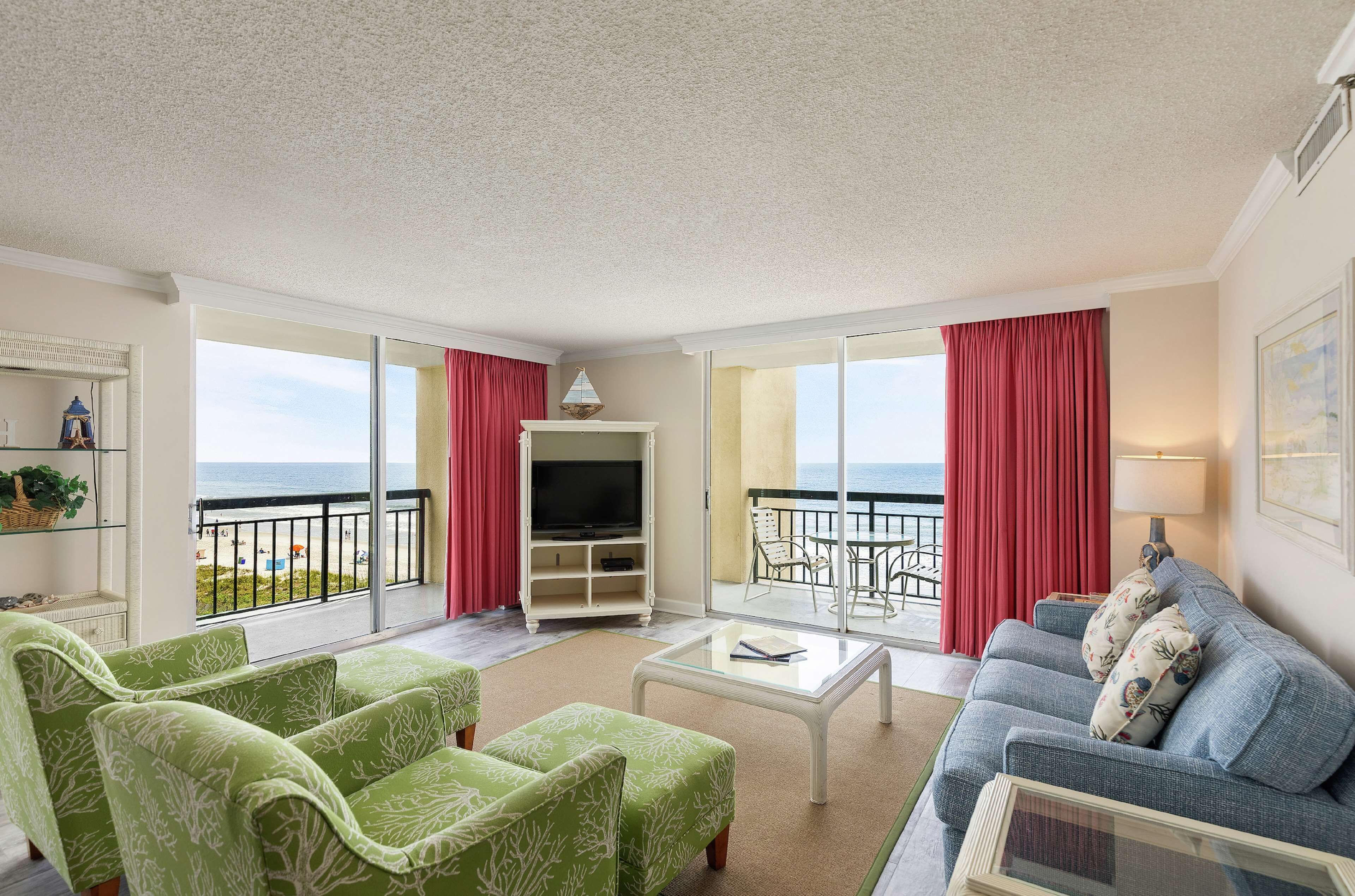 Een ruime woonkamer met balkon, televisie en bank.