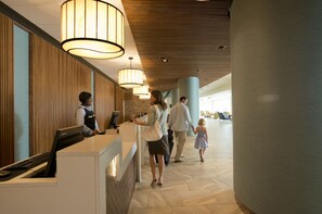 A hotel reception area with a modern design, featuring a reception desk, large pendant lights, and a spacious lobby with a high ceiling and columns. - Kingston Plantation Condos (Myrtle Beach)