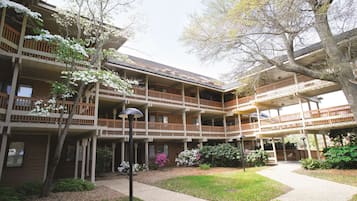 A multi-story building with balconies, a covered walkway, and surrounding greenery.
