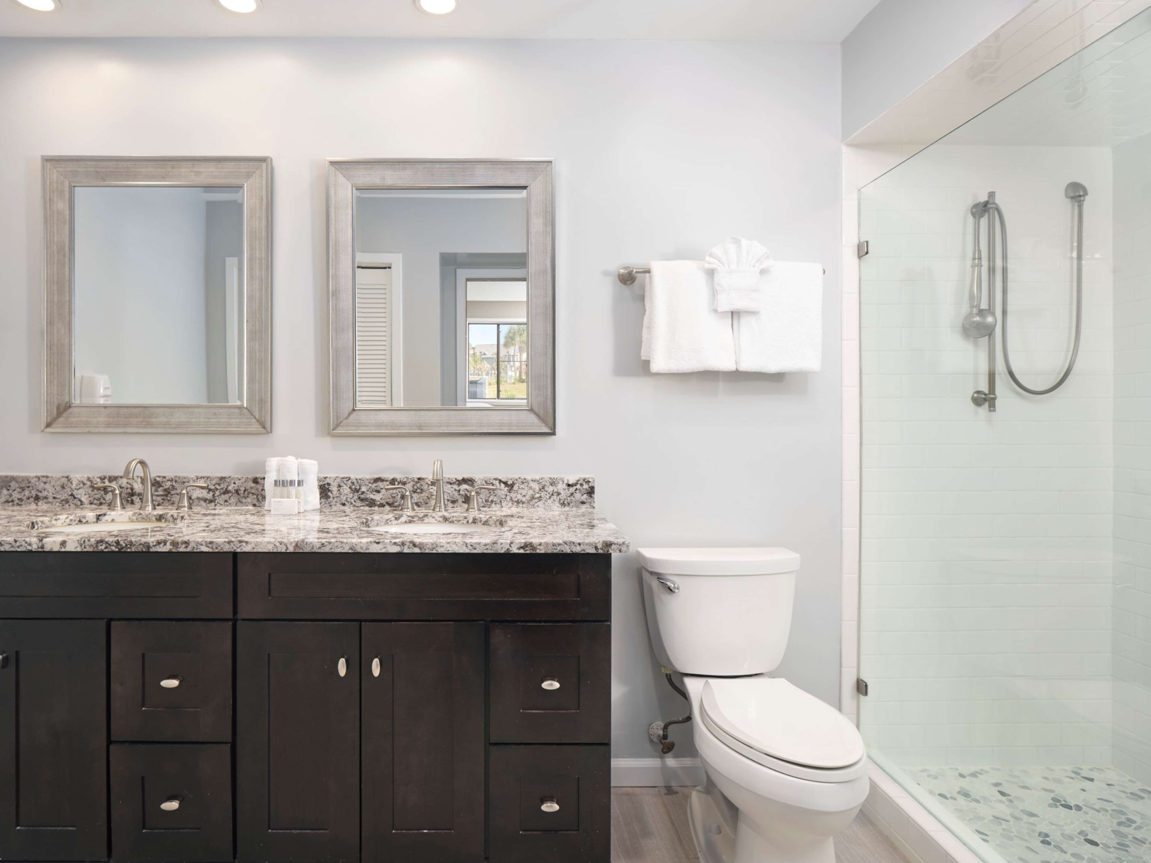 A bathroom with dark wooden cabinets, a white toilet, and a glass-enclosed shower.
