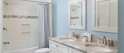 A bathroom with a bathtub, toilet, and two sinks with mirrors above.