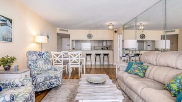 Una sala de estar con sofá, sillón, mesa de centro y un comedor con sillas y una mesa.