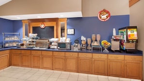 A breakfast bar with a coffee machine, microwave, and various food items. - AmericInn by Wyndham Webster City (Webster City)