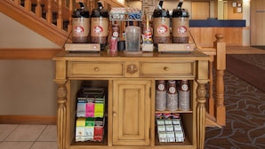 A coffee station with multiple dispensers and a variety of coffee products. - AmericInn by Wyndham Webster City (Webster City)