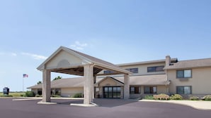 A two-story building with a covered entrance and a flagpole with an American flag. - AmericInn by Wyndham Webster City (Webster City)
