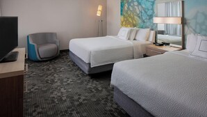 A hotel room with two beds, a desk with a computer, a chair, a floor lamp, and a large abstract painting on the wall. - Courtyard by Marriott Daytona Beach Speedway/Airport (Daytona Beach)