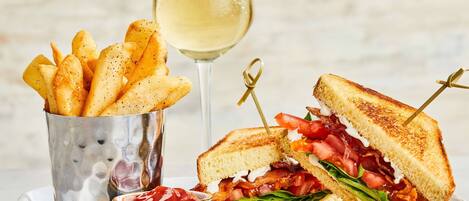 A plate with a grilled sandwich, fries, and a glass of white wine.