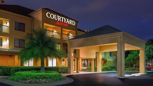 A Courtyard Marriott hotel with a covered entrance, a palm tree, and well-lit windows. - Courtyard by Marriott Daytona Beach Speedway/Airport (Daytona Beach)