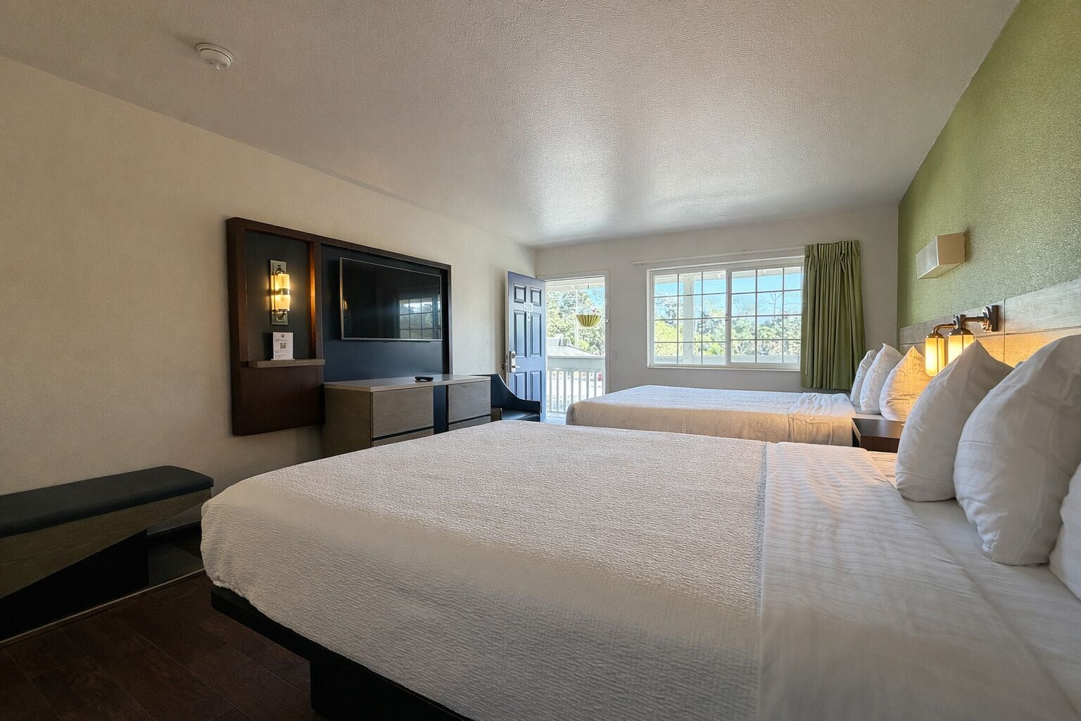 Habitación de hotel con dos camas, televisión, escritorio y ventana con vistas.
