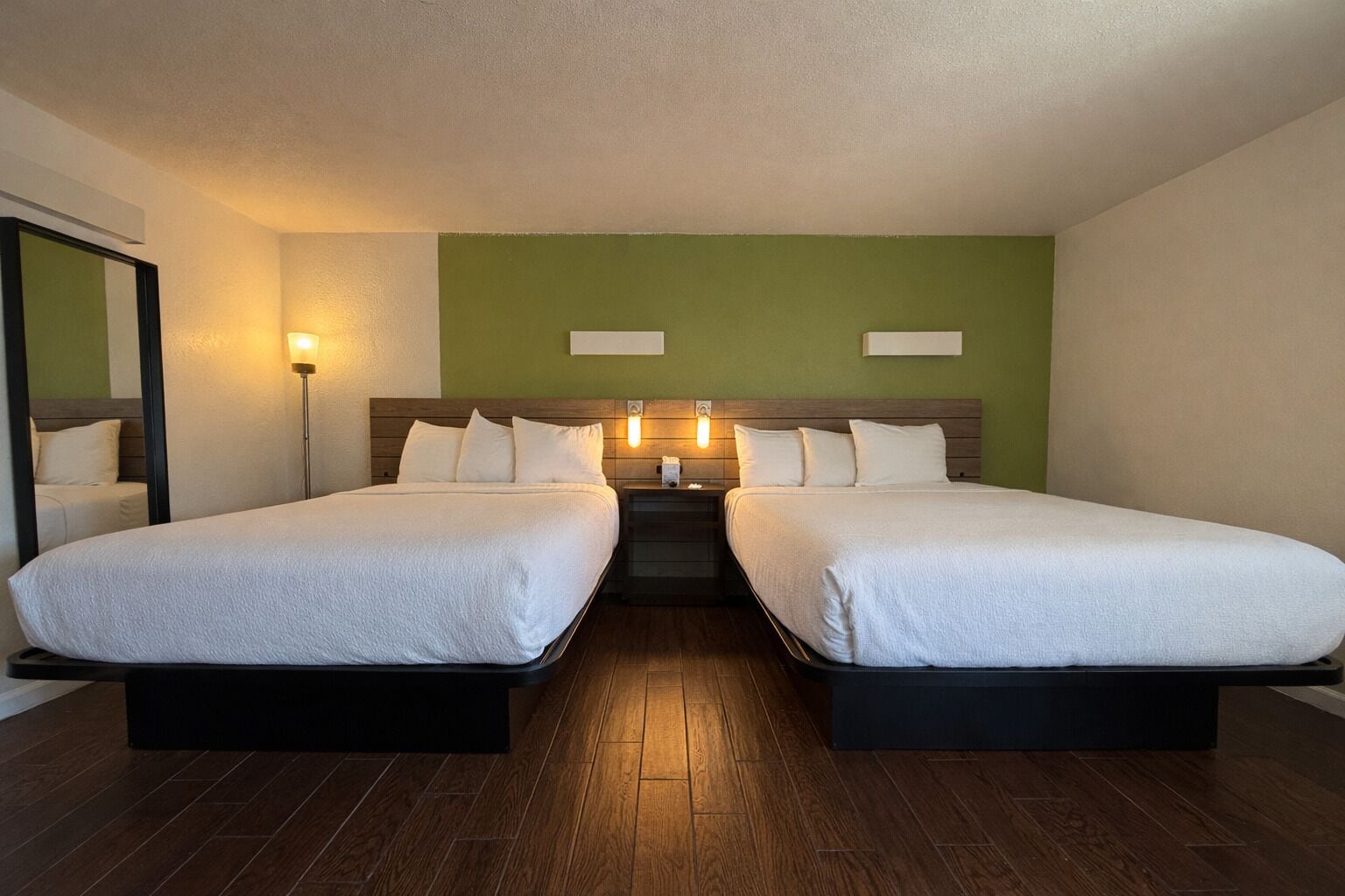 A double room with two beds, a nightstand, a lamp, and a mirror.