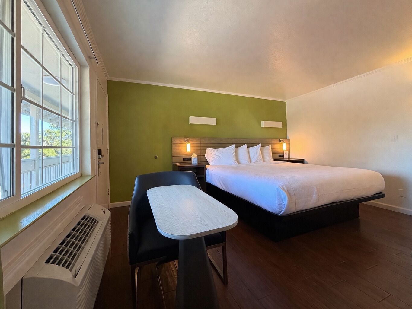 A bedroom with a bed, a desk, and a window.