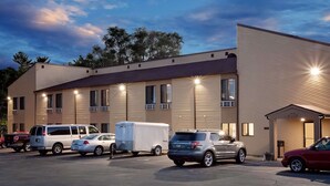 Un hotel con varios espacios de estacionamiento, una caravana y un edificio de techo plano con ventanas grandes.