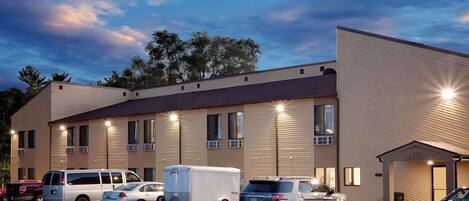 A hotel with multiple parking spaces, a trailer, and a building with a flat roof and large windows.