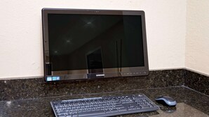Monitor Samsung montado en una pared, un teclado y un ratón sobre una encimera de granito.