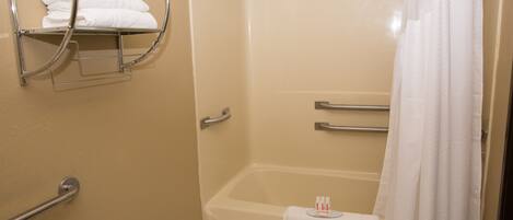 A bathroom with a bathtub, a towel rack with folded towels, and a shower curtain.