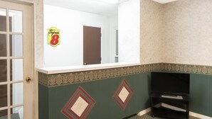 A hotel lobby with a reception desk, a door, and a wall with a decorative border.
